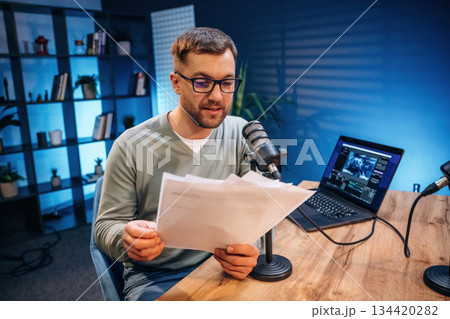 Reading the text. Man with microphone in the studio, conception of podcast Reading the text. Man with microphone in the studio, conception of podcast 134420282