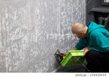 Close-up shot capturing a construction worker applying decorative plaster to a wall with a trowel 134420414