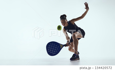 Female padel player controlling ball close to racket in studio. 134420572