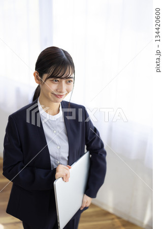 ノートパソコンを抱えて微笑む若いビジネスウーマン ノートパソコンを抱えて微笑む若いビジネスウーマン 134420600