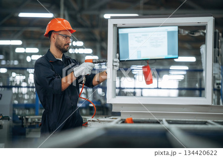 Maintaining the window, using screwdriver. Man is working in the modern factory Maintaining the window, using screwdriver. Man is working in the modern factory 134420622