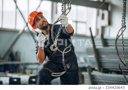 Strong cables are hanging. Man is working in the modern factory 134420643
