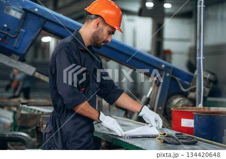 By the machine, operator is taking notes. Man is working in the modern factory By the machine, operator is taking notes. Man is working in the modern factory 134420648