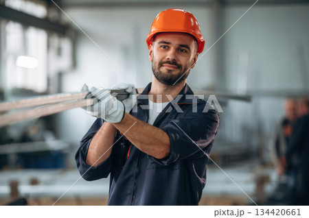 Holding metal pieces, planks. Man is working in the modern factory 134420661