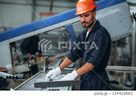 By the machine, operator is taking notes. Man is working in the modern factory By the machine, operator is taking notes. Man is working in the modern factory 134420663