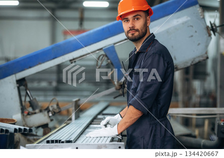 By the machine, operator is taking notes. Man is working in the modern factory By the machine, operator is taking notes. Man is working in the modern factory 134420667