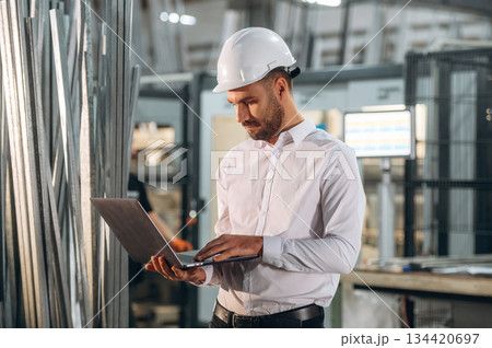 Laptop is in hands. Man is working in the modern factory Laptop is in hands. Man is working in the modern factory 134420697