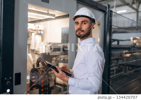Manager is in white shirt. Man is working in the modern factory Manager is in white shirt. Man is working in the modern factory 134420707