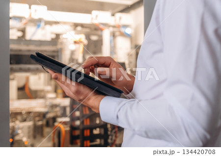 Digital tablet in hands. Close up view of man that is working in the modern factory Digital tablet in hands. Close up view of man that is working in the modern factory 134420708