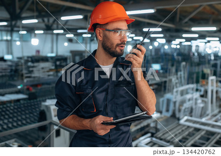 Giving instructions, using radio, walkie talkie. Man is working in the modern factory Giving instructions, using radio, walkie talkie. Man is working in the modern factory 134420762