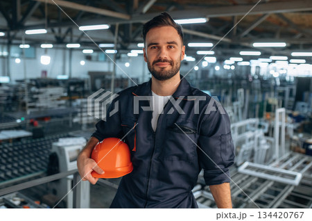 Portrait, front view, standing. Man is working in the modern factory Portrait, front view, standing. Man is working in the modern factory 134420767