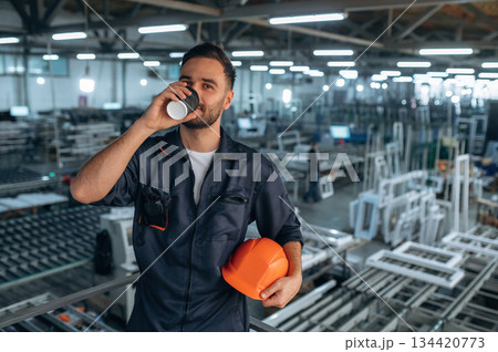 Break time, with fresh drink. Man is working in the modern factory Break time, with fresh drink. Man is working in the modern factory 134420773