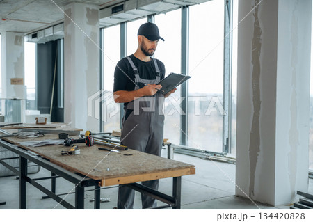 By the table. A man is renovating an unfinished room 134420828