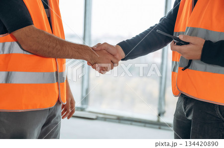 Close up view of two construction site workers making handshake, meet Close up view of two construction site workers making handshake, meet 134420890
