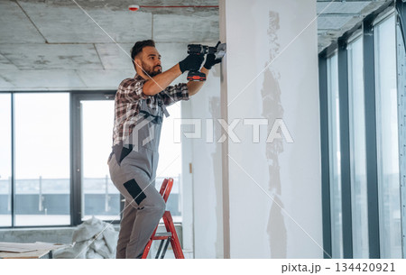 Using the drill. A man is renovating an unfinished room 134420921