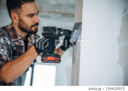 Using the drill. A man is renovating an unfinished room 134420925