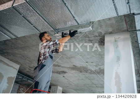 Installing the ceiling. A man is renovating an unfinished room 134420928