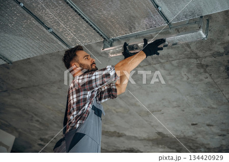 Installing the ceiling. A man is renovating an unfinished room Installing the ceiling. A man is renovating an unfinished room 134420929