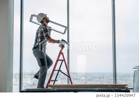 On the ladder. A man is renovating an unfinished room On the ladder. A man is renovating an unfinished room 134420947