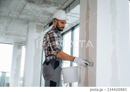 Puttying the wall. A man is renovating an unfinished room 134420983