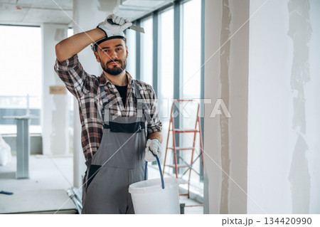 Taking a break. A man is renovating an unfinished room Taking a break. A man is renovating an unfinished room 134420990