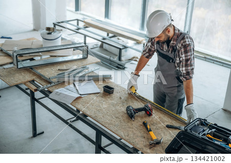 Top view, standing by the table. A man is renovating an unfinished room Top view, standing by the table. A man is renovating an unfinished room 134421002