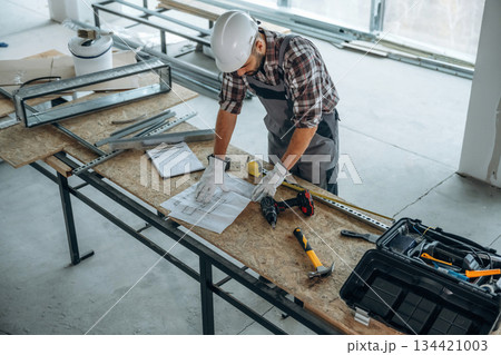 Top view, standing by the table. A man is renovating an unfinished room Top view, standing by the table. A man is renovating an unfinished room 134421003