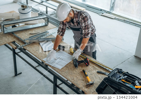 Top view, standing by the table. A man is renovating an unfinished room Top view, standing by the table. A man is renovating an unfinished room 134421004