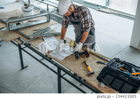 Top view, standing by the table. A man is renovating an unfinished room 134421005