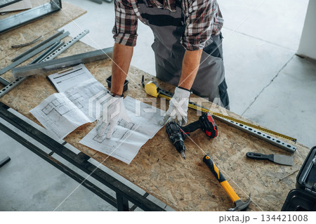Focused, tools. Close up view of worker that is renovating unfinished room 134421008