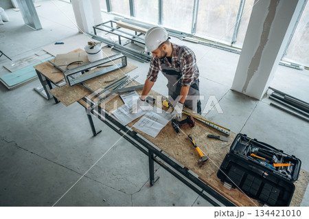 Wooden table with metal foundation. A man is renovating an unfinished room Wooden table with metal foundation. A man is renovating an unfinished room 134421010