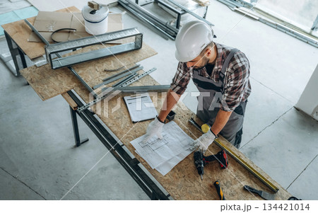 By the table. A man is renovating an unfinished room 134421014