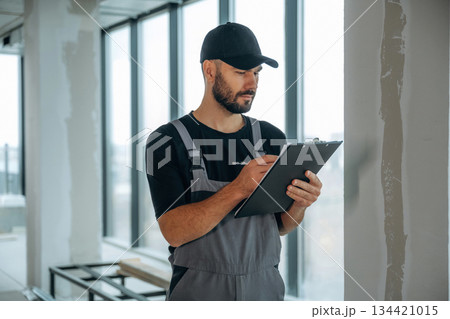 Notepad is in hands. A man is renovating an unfinished room 134421015