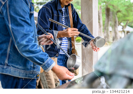 神社で手水を使うシニア夫婦 134421214