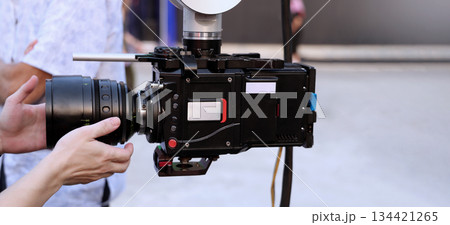 Behind the scenes of movie shooting or video production and film crew team with camera equipment at outdoor location. Video camera with professional robotic arm. BTS of Filming camera setup at outdoor 134421265