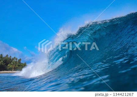 Energetic surf soaring over coral reef with dazzling sunlight reflections 134421267
