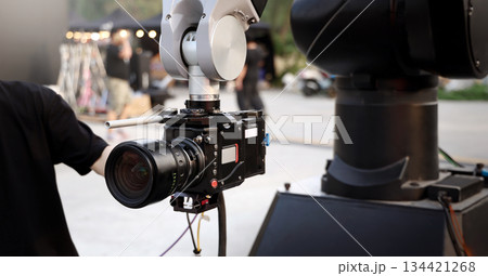 Behind the scenes of movie shooting or video production and film crew team with camera equipment at outdoor location. Video camera with professional robotic arm. BTS of Filming camera setup at outdoor Behind the scenes of movie shooting or video production and film crew team with camera equipment at outdoor location. Video camera with professional robotic arm. BTS of Filming camera setup at outdoor 134421268