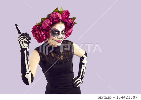 Beautiful cheerful woman with Mexican-style Halloween face art has new funny idea. 134421307