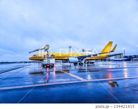 Yellow cargo airplane undergoing winter deicing on airport apron. Aircraft maintenance operation during cold weather aviation safety procedures. High quality photo 134421815