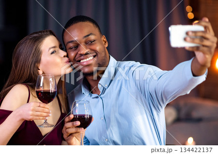 Young multiracial couple in love taking selfie while having romantic dinner at restaurant. Smiling interracial lovers drinking wine and having fun during date, celebrating Valentine's day together Young multiracial couple in love taking selfie while having romantic dinner at restaurant. Smiling interracial lovers drinking wine and having fun during date, celebrating Valentine's day together 134422137