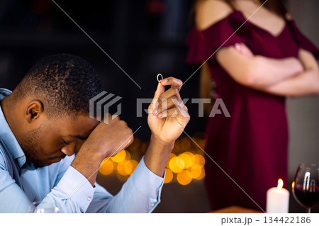 Desperate Black Man Sitting At Table With Ring In Hand After Girlfriend Refused His Proposal And Not Accepting Engagement Offer. Young African American Guy Feeling Lonely And Depressed, Cropped Image Desperate Black Man Sitting At Table With Ring In Hand After Girlfriend Refused His Proposal And Not Accepting Engagement Offer. Young African American Guy Feeling Lonely And Depressed, Cropped Image 134422186