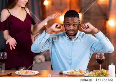 Interracial Couple Arguing. Young Multicultural Lovers Having Conflict During Date In Restaurant, Annoyed Black Man Closing Ears With Fingers, Ignoring His Complaining Girlfriend, Free Space Interracial Couple Arguing. Young Multicultural Lovers Having Conflict During Date In Restaurant, Annoyed Black Man Closing Ears With Fingers, Ignoring His Complaining Girlfriend, Free Space 134422188