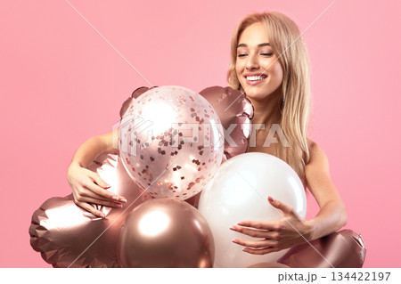 Graceful blonde birthday lady posing with colorful balloons over pink studio background. Elegant young woman expressing happiness, enjoying holiday or party, celebrating special occassion Graceful blonde birthday lady posing with colorful balloons over pink studio background. Elegant young woman expressing happiness, enjoying holiday or party, celebrating special occassion 134422197