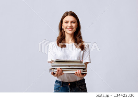Waste Sorting. Portrait Of Beautiful Young Woman Holding Stack Of Old Magazines In Hands, Collecting Paper Garbage For Recycling, Smiling Eco-Volunteer Lady Standing Over Light Studio Background Waste Sorting. Portrait Of Beautiful Young Woman Holding Stack Of Old Magazines In Hands, Collecting Paper Garbage For Recycling, Smiling Eco-Volunteer Lady Standing Over Light Studio Background 134422330