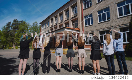 Group of happy students waving goodbye to their school on the last day, celebrating graduation and the end of the academic year Group of happy students waving goodbye to their school on the last day, celebrating graduation and the end of the academic year 134422413