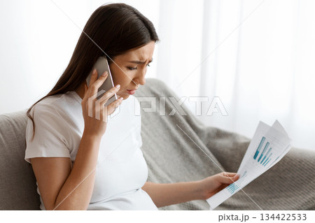 Remote Work During Pregnancy. Stressed Pregnant Woman Working With Papers And Laptop, Worried Expectant Lady Sitting On Couch In Living Room And Talking On Cellphone, Having Business Problems Remote Work During Pregnancy. Stressed Pregnant Woman Working With Papers And Laptop, Worried Expectant Lady Sitting On Couch In Living Room And Talking On Cellphone, Having Business Problems 134422533