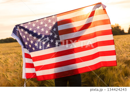 Silhouette of Young Woman Holding USA Flag in Field at Sunset Silhouette of Young Woman Holding USA Flag in Field at Sunset 134424243