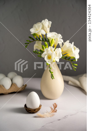 gSpring, Easter background. White freesias flowers in a vase with white eggs. gSpring, Easter background. White freesias flowers in a vase with white eggs. 134424364