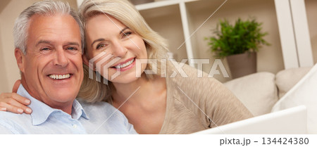 Happy Senior Man and Woman Couple Smiling at Home Using a Computer Happy Senior Man and Woman Couple Smiling at Home Using a Computer 134424380