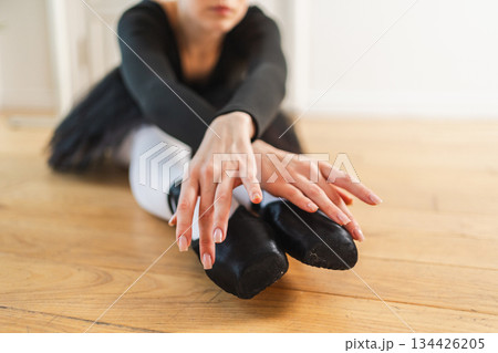 Young ballerina in tutu skirt stretching practicing ballet positions dancing in dance class. Young classical dancer woman in dance studio. Ballet class training Ballet school concept 134426205